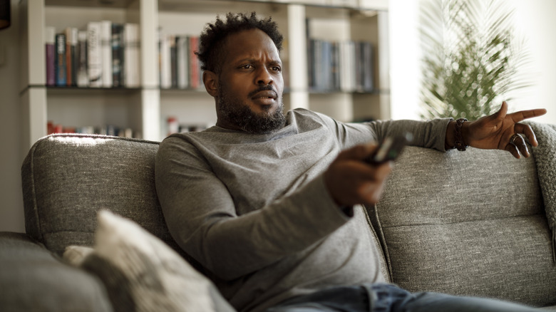 frustrated man holding TV remote