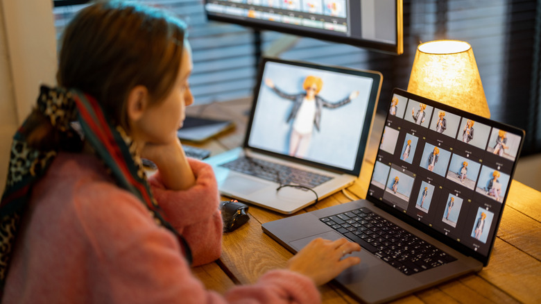 Young woman working on laptop and desktop computers editing photos