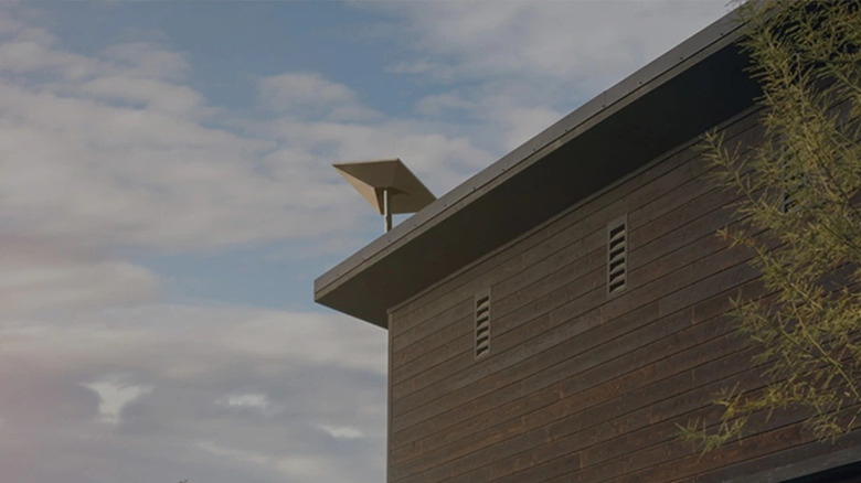 Starlink dish mounted on roof with cloudy skies in the background