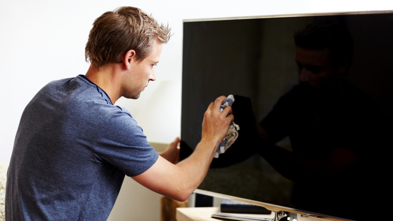 Man cleaning flat-screen TV with cloth