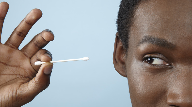 holding up and looking at a cotton swab