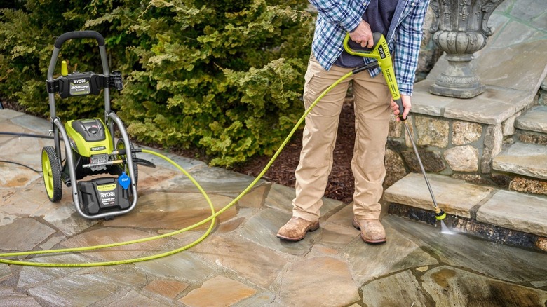 Person cleaning steps with pressure washer