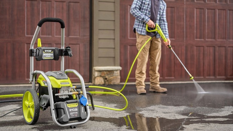 Person using pressure washer to clean driveway