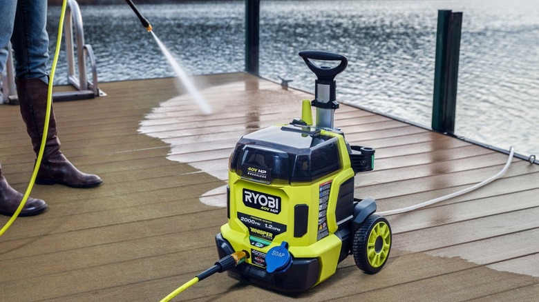 Person washing dock with pressure washer