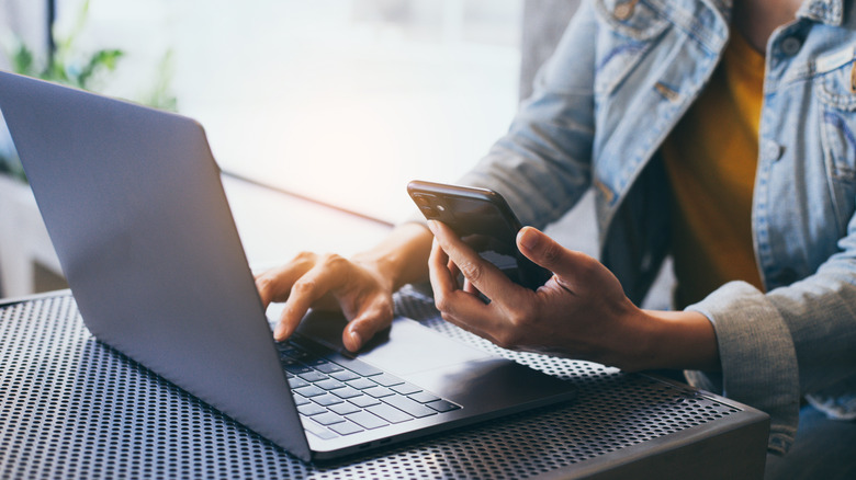 Person looking at laptop and phone