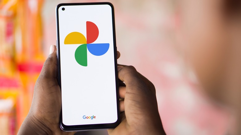 Person holding smartphone with Google Photos logo