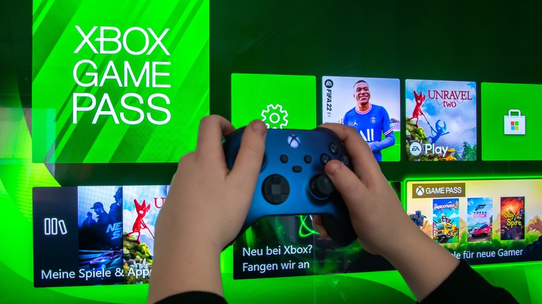 Xbox controller being used in front of TV diplaying Xbox Game Pass