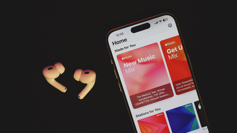 Apple Music app on an iPhone with AirPods next to it