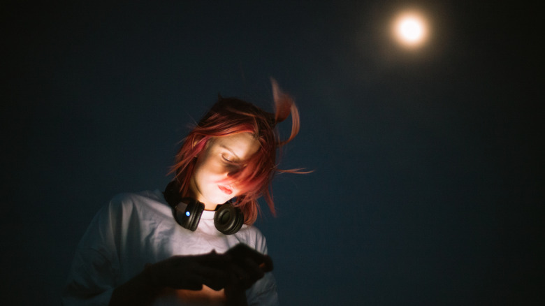 Woman with smartphone moon in sky