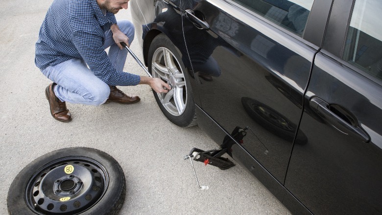 A man changing his car tire to a spare tire