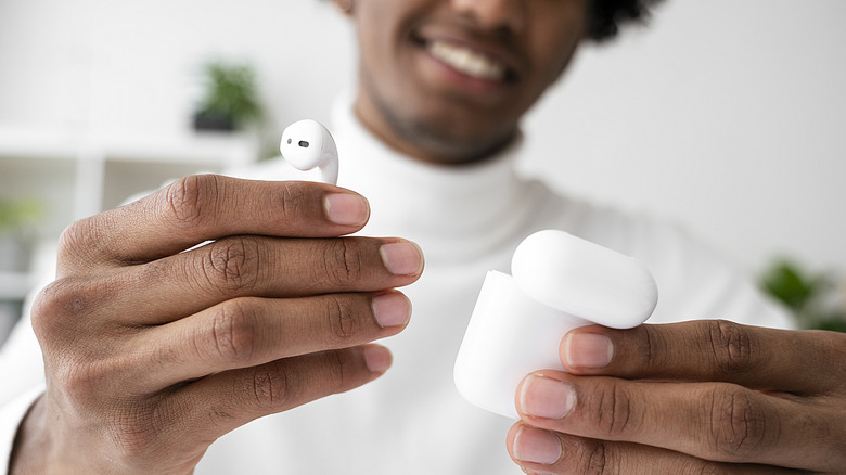 man holding AirPod out of case