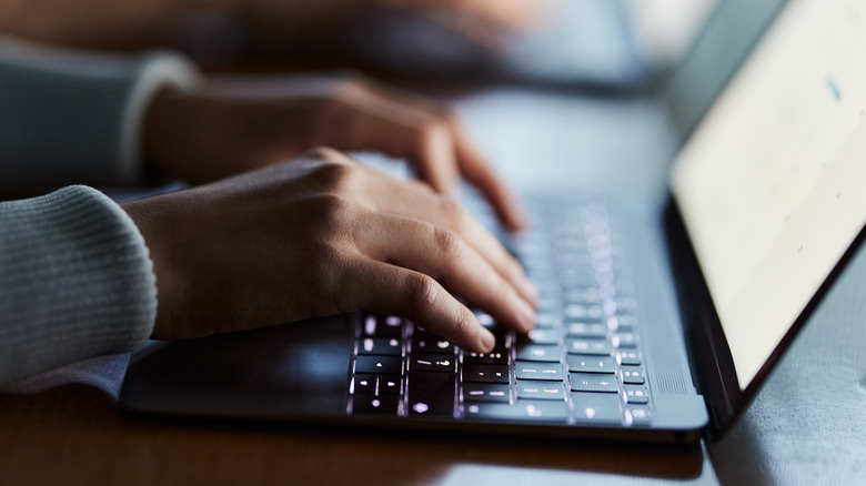 hands typing on laptop keyboard