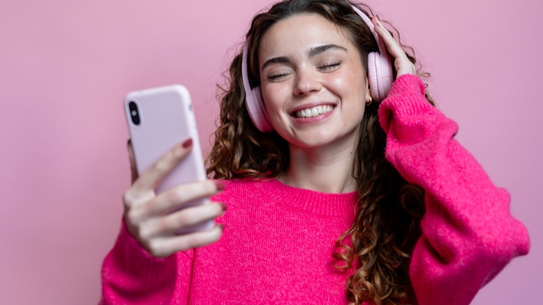 Girl wearing headphones holding iPhone