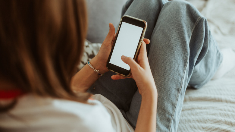 12 year old girl laying on a couch holding mobile phone