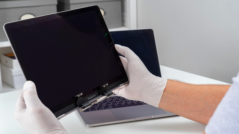 repair technician holding a MacBook screen replacement