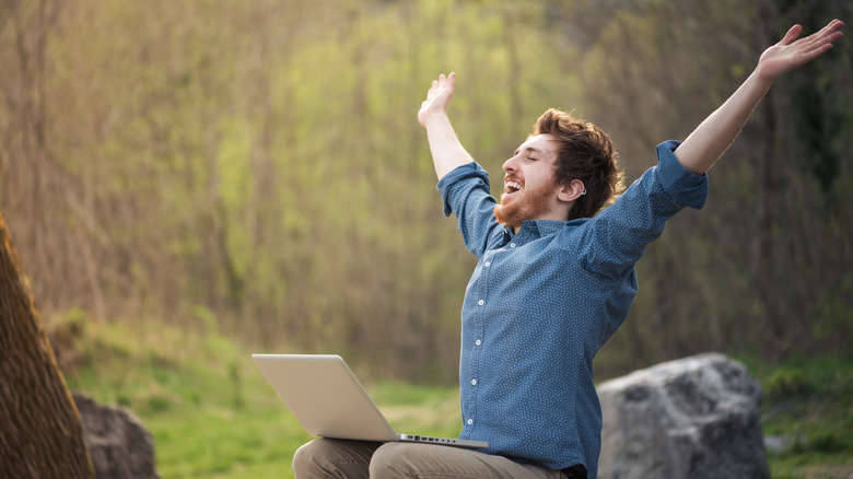 Cheerful person with laptop outdoors