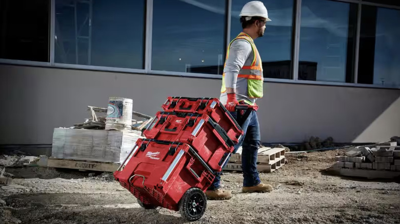 Man dragging Milwaukee Packout toolboxes across jobsite