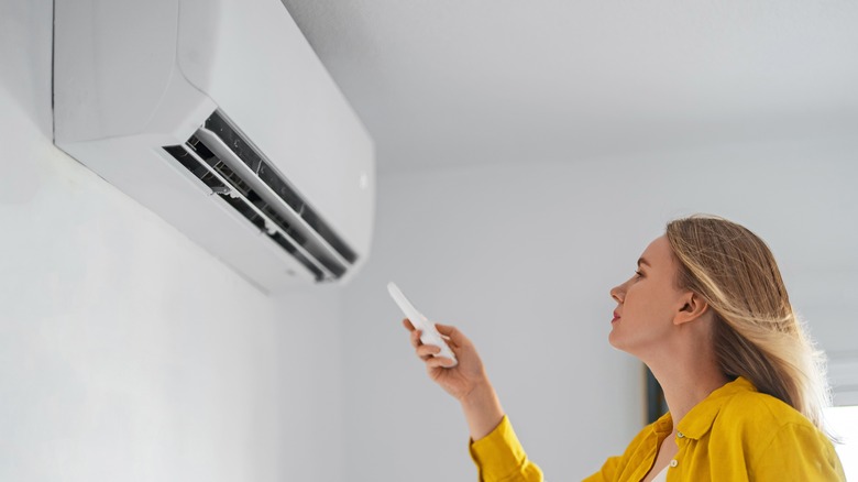 Woman adjusting air conditioner