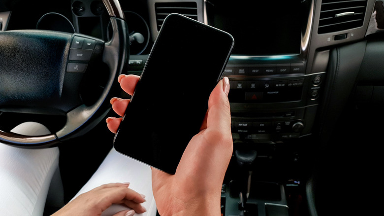 Person holding iPhone X in car