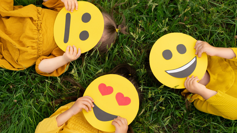 children lay in grass holding masks