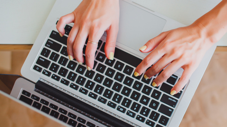 woman typing on a macbook