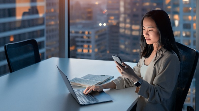 woman using phone and laptop