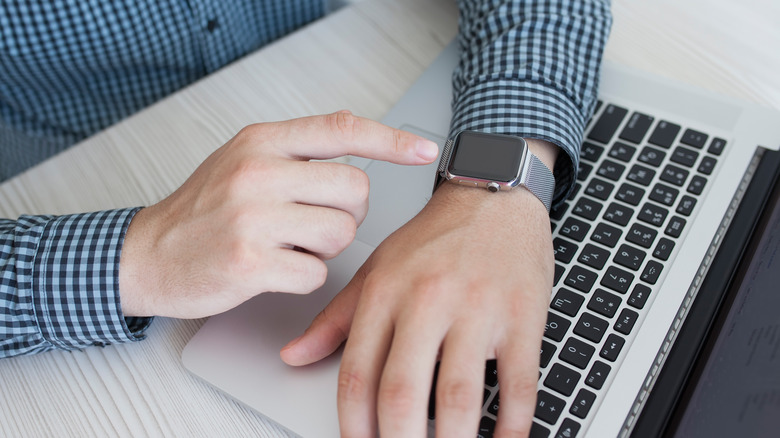 Man using Apple Watch with MacBook