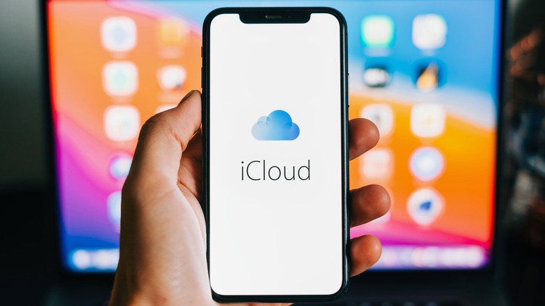 iPhone with iCloud logo on screen, in front of a Mac screen