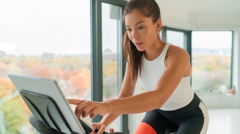 Woman tapping on Peloton touchscreen