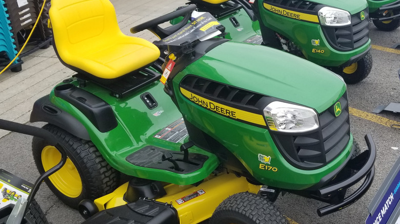 John Deere riding lawn mowers parked in a parking lot