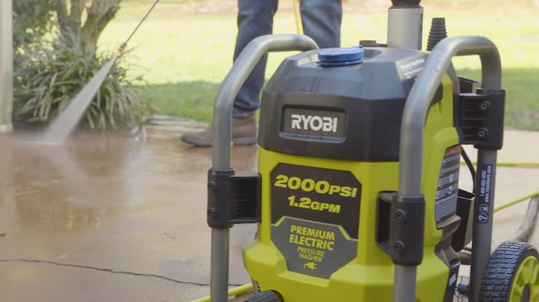 A person using a Ryobi power washer on concrete.