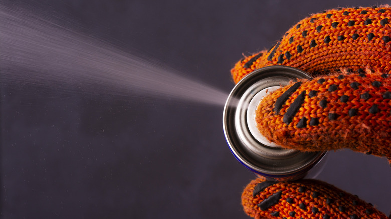 A person spraying a can of WD-40.