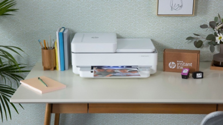 HP Instant Ink package and cartridges near printer.