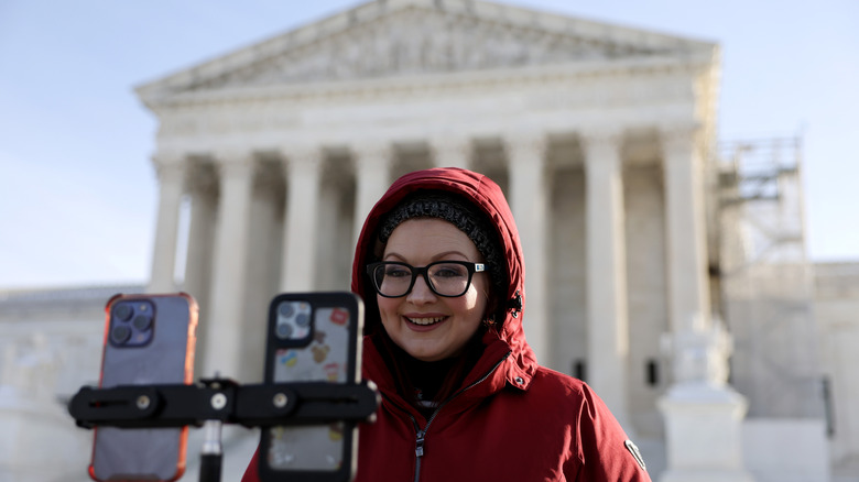 A woman records video in front of the Supreme Court