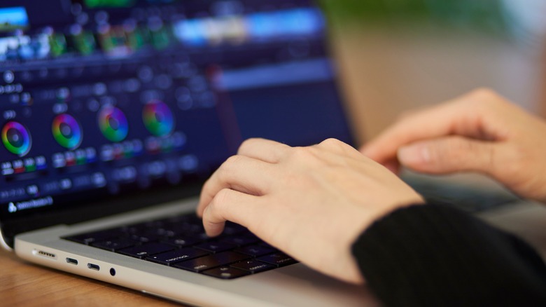 Woman typing on keyboard while editing video