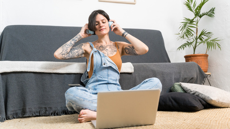 Woman looking at laptop while putting on headphones