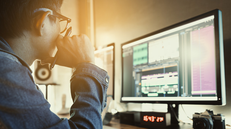 Man sitting with stylus looking at video editing timeline