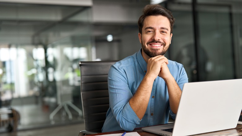 Man happily sitting at a desk with his laptop open