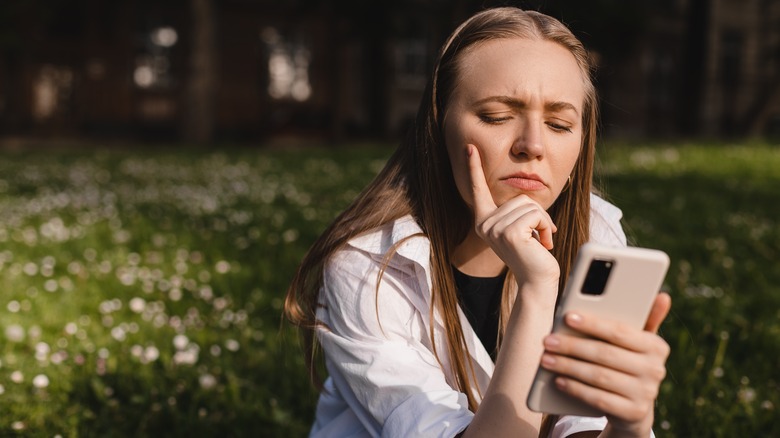 Woman looking at pink phone trying to make a decision