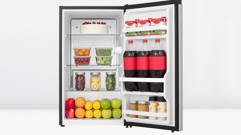 Hisense 3.3CF Sliver Mini Fridge with the door open, fully stocked with food including cola bottles, milk, fruit, vegetables and a large cake