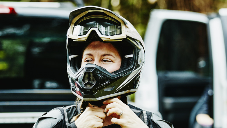 A person putting on a dirt bike helmet.