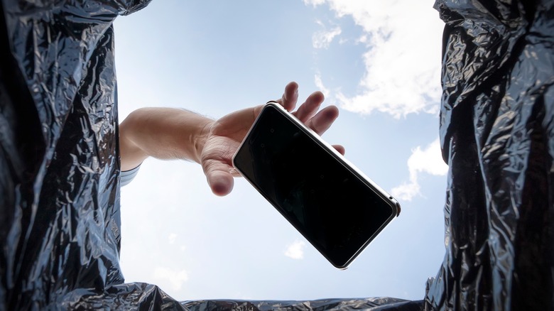 smartphone being thrown in trash