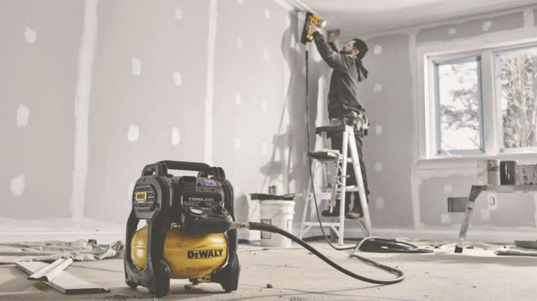 Carpenter using a DeWalt 2.5-Gallon 140 psi 20V Cordless Air Compressor﻿ to nail trim in a new home