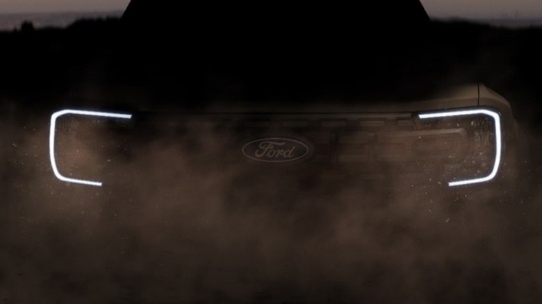 bracket LED headlights and ford grille logo visible in a cloud of dust in low light