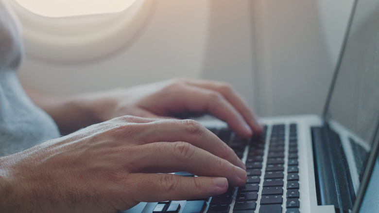 Person using laptop on plane