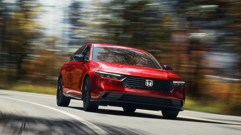 A red 2025 Honda Accord sport-l hybrid being driven on a curvy road