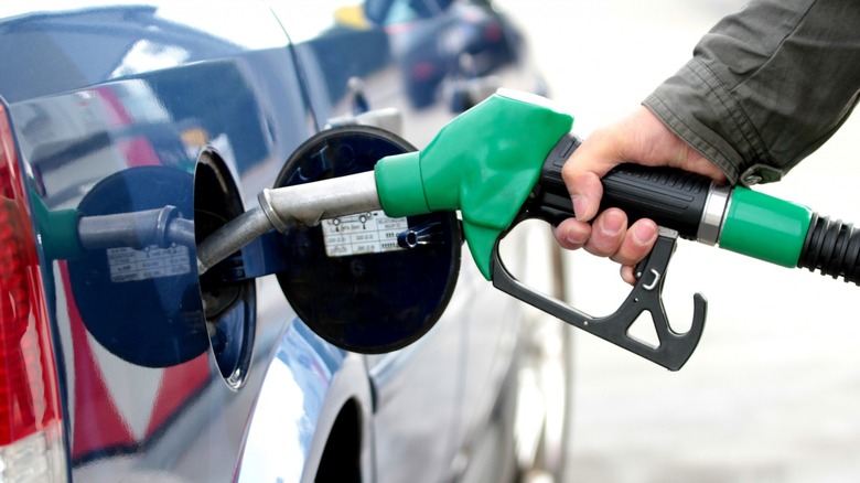 Hand putting gas in a car's fuel tank.