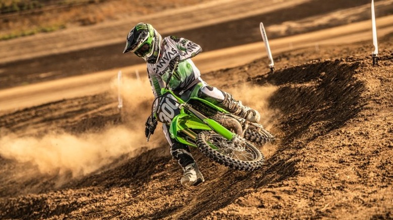 A Kawasaki KX85 rider negotiation a 180-degree turn on a motocross track.