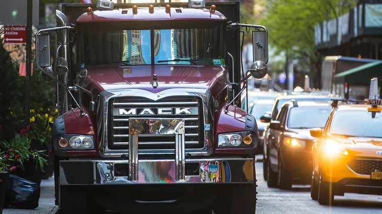 Red Mack Granite truck parked on a city street with cars driving past