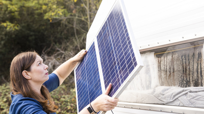 Woman mounting solar panel to trailer